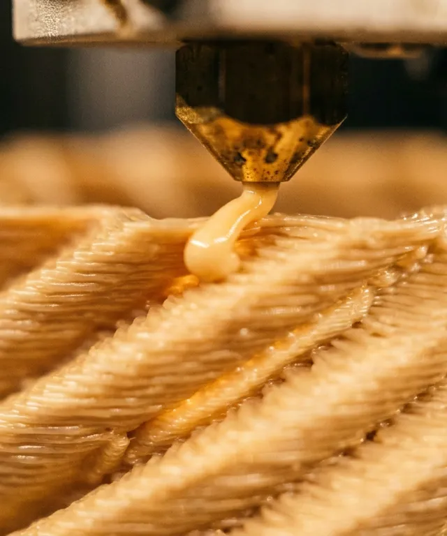 Buse d'imprimante 3D déposant du PLA beige couche après couche